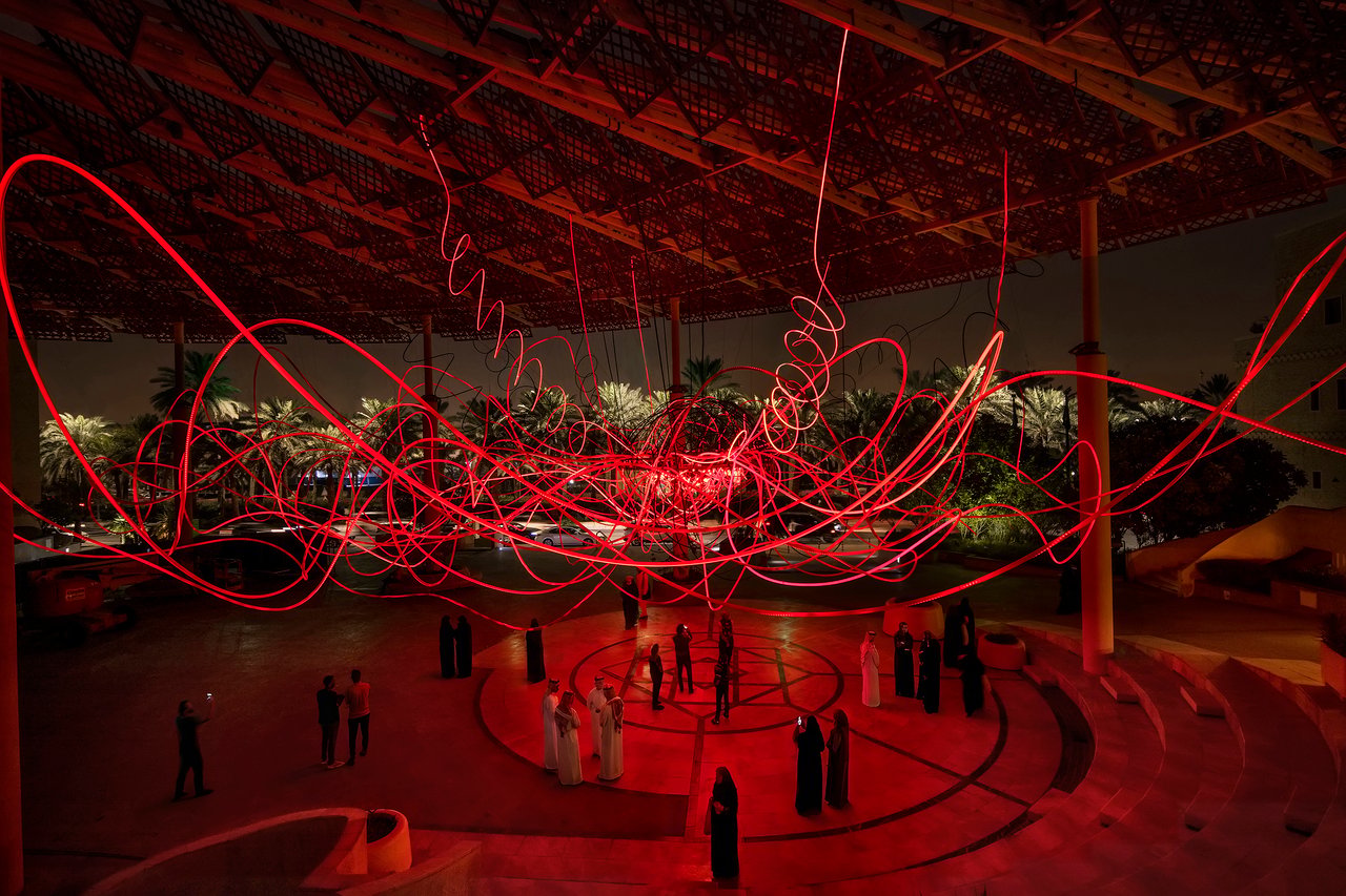 Grimanesa Amorós AMPLEXUS — monumental 100-foot LED light installation at Noor Riyadh Festival, Diplomatic Quarter, Saudi Arabia. Glowing red tubing inspired by Riyadh's desert sunrises and sunsets wraps the circular columns of the Cultural Palace, blending traditional Islamic architecture with light art. Public light sculpture by Grimanesa Amorós, 2022.