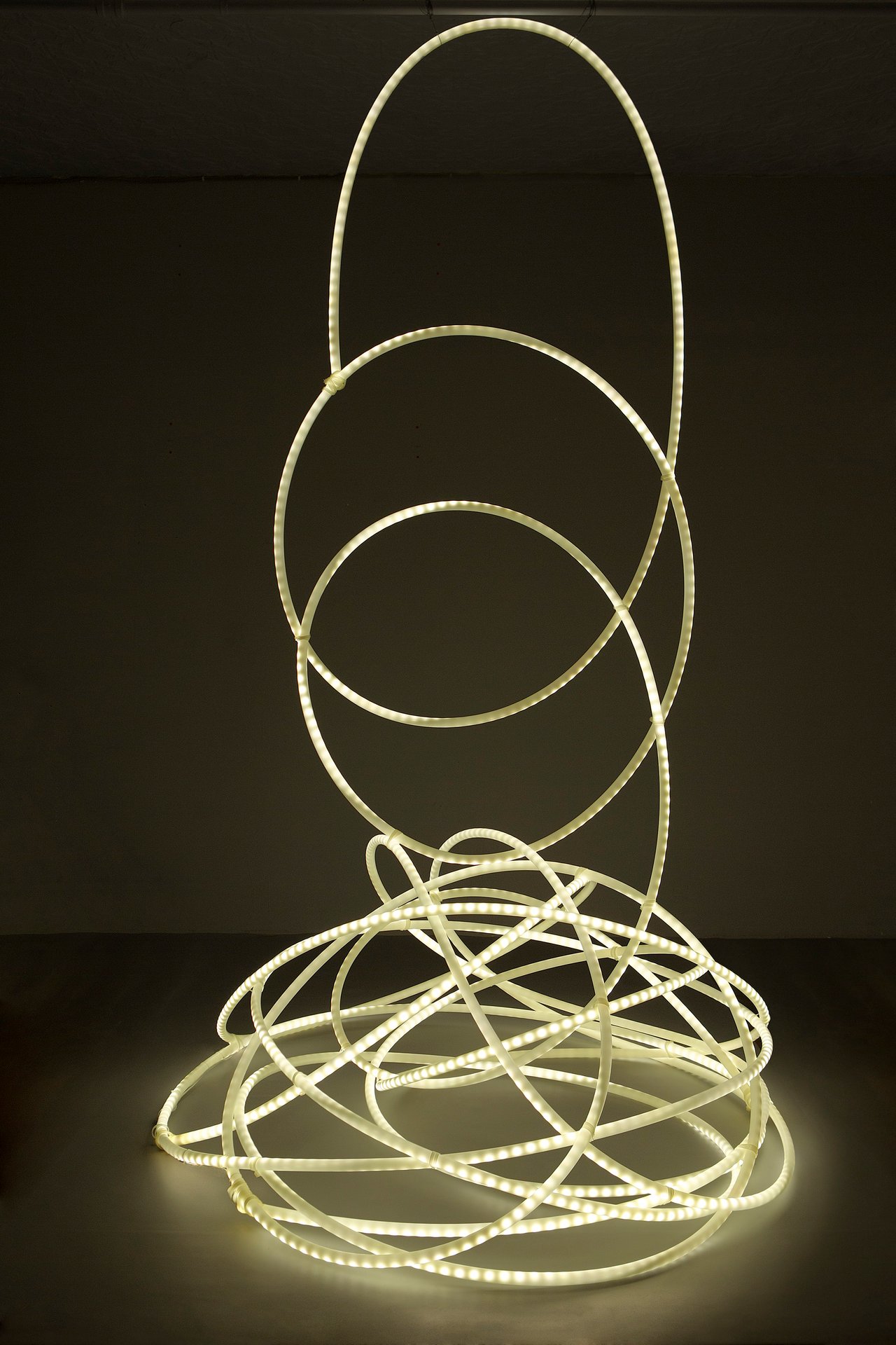 Grimanesa Amorós AUREUM, 48 x 48 x 120-inch light sculpture made of LEDs, diffusion material, and custom lighting sequence, featuring an enchanting golden lighting sequence that continuously evolves to cast a mesmerizing aura, inviting viewers to explore the profound impact of metaphorical light and unlock new realms of insight through the interplay of light and perception. Light sculpture by Grimanesa Amorós, 2020.