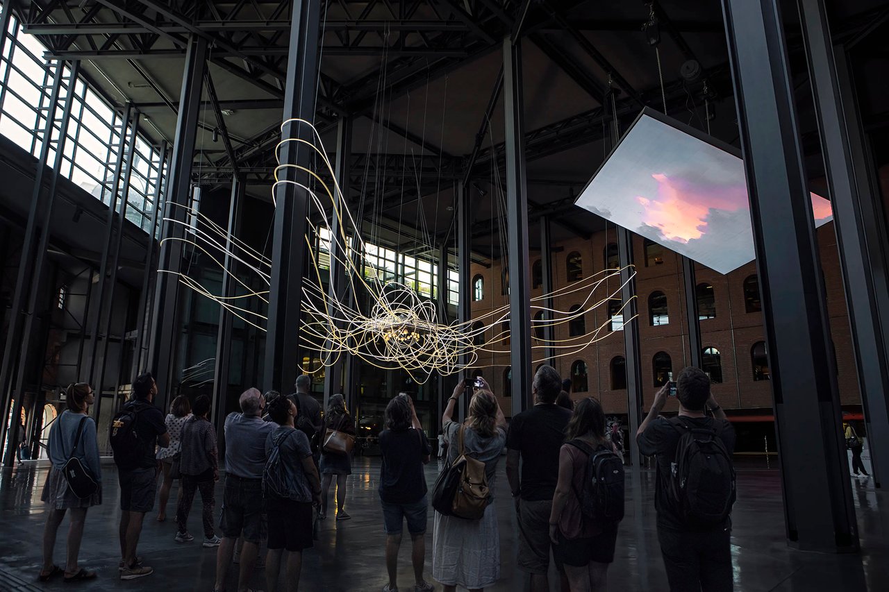 Grimanesa Amorós SCIENTIA — monumental LED sculpture and public art light sculpture at Azkuna Zentroa cultural center, Bilbao, Spain. Spanning 60 x 35 x 25 feet, glowing LED art fills the grand historic atrium with forms exploring knowledge, fire, water, earth, and light. Diffusive and reflective surfaces transform at dusk into mirror-like planes. Site-specific light sculpture installation by Grimanesa Amorós.
