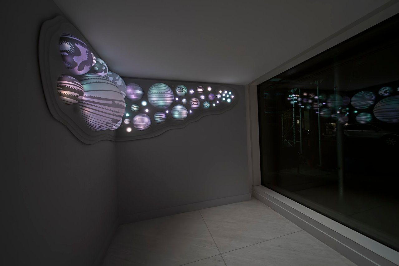 Grimanesa Amorós IUGO, an 11-foot LED sculpture and light sculpture in the lobby of 176 East 82nd Street, ODA Architecture / Nexus building, Upper East Side, New York, 2021. Made of stainless steel, diffusion and reflective material, and LEDs, the cupola forms are silkscreened with aerial views of Tel Aviv's vineyards, citrus groves, and olive fields, connecting Manhattan and Tel Aviv through shared geography and light. LED sculpture by Grimanesa Amorós.