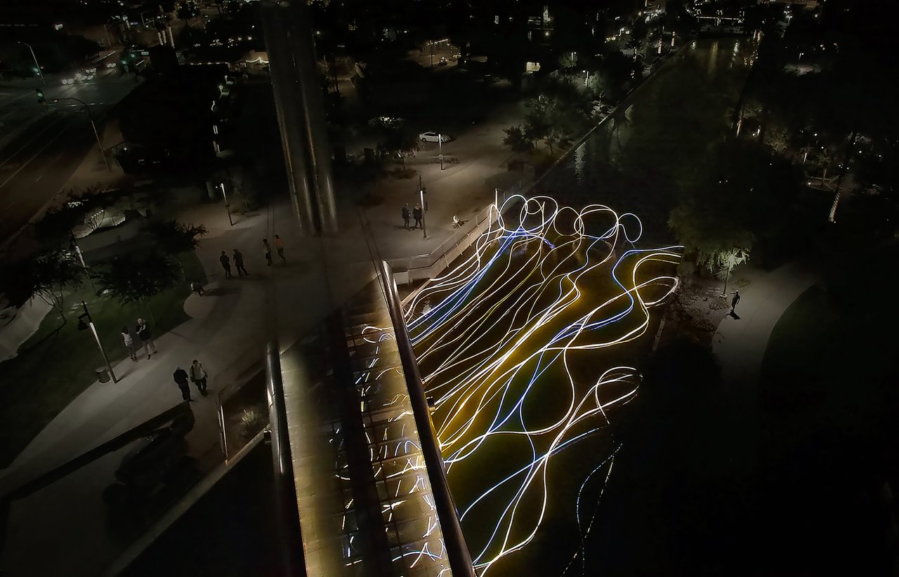 Grimanesa Amorós GOLDEN WATERS, 40 x 164 x 18-foot public art light sculpture and outdoor LED sculpture floating above the Arizona Canal at the Soleri Bridge, Scottsdale, AZ, 2015. LED tubing in diffusion and reflective material rises from the canal waters as if born of them, honoring the ancient Hohokam people's irrigation canals. Commissioned by Scottsdale Public Art and winner of the 2016 CODAaward. Outdoor light sculpture by Grimanesa Amorós.