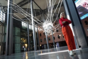 Monumental Sculpture Artist Grimanesa Amoros in Red outfit in front of monumental LED Light sculpture SCIENTIA