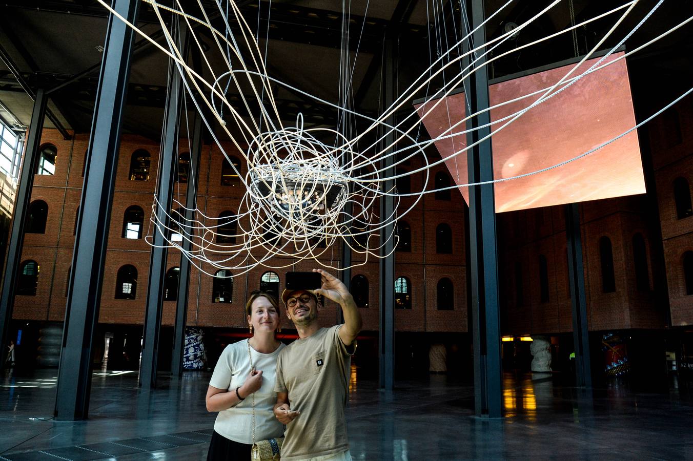 Man and woman take selfie in front of light artist grimanesa amoros monumental sculpture SCIENTIA in Bilbao Spain at Azkuna Zentroa apart of wellbeing summit